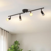 Black ceiling light fixture with four bulbs on a white ceiling, with a plant and curtain in the foreground.